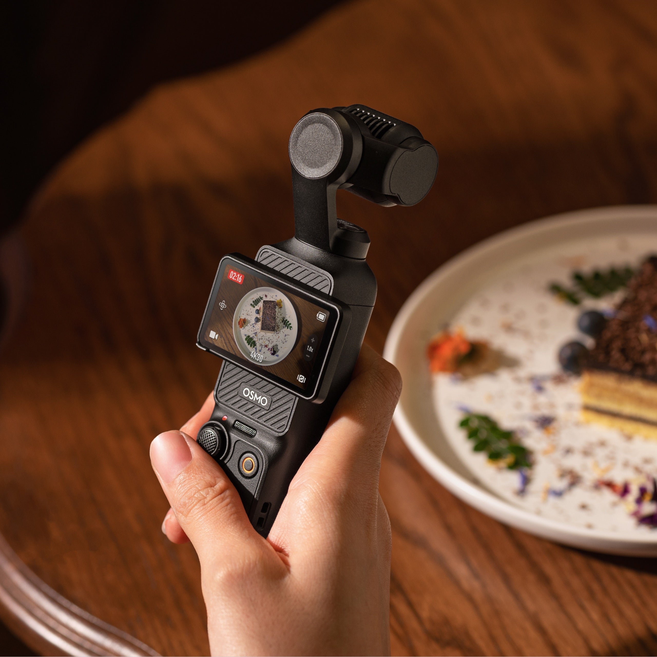 Caméra tenue à la main pour filmer une assiette au restaurant