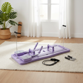 Planche de Pilates Reformer violette dépliée sur un tapis dans un appartement lumineux