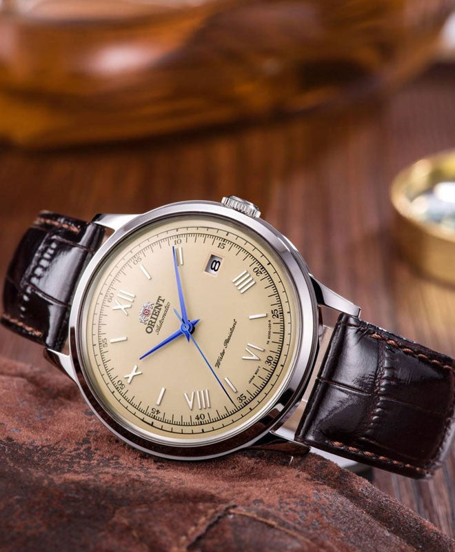 Montre Bambino 40,5 mm posée sur un plateau en bois, guichet de date à 3 h